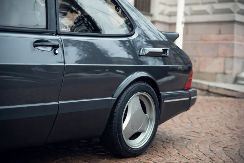 Dark sedan rear view, classic car design, shiny wheels.