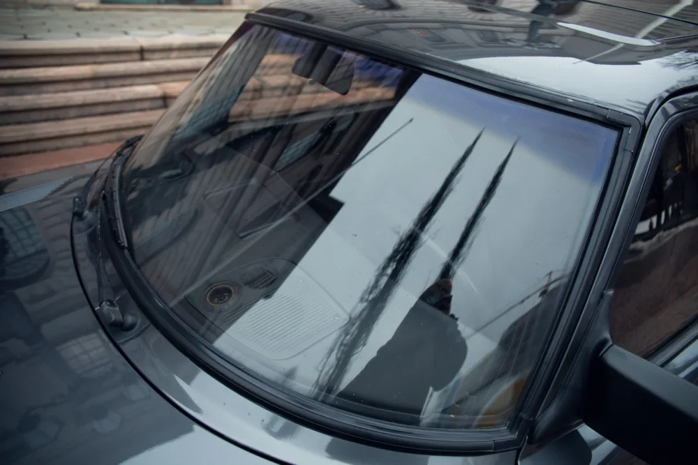 Car windshield with visible wipers and reflections.