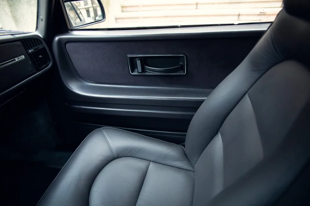 Car interior with leather seat and door handle.