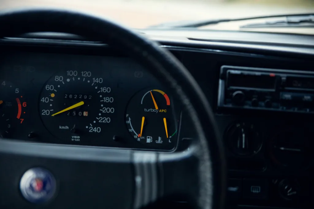 Vintage car dashboard with turbo gauge and steering wheel.