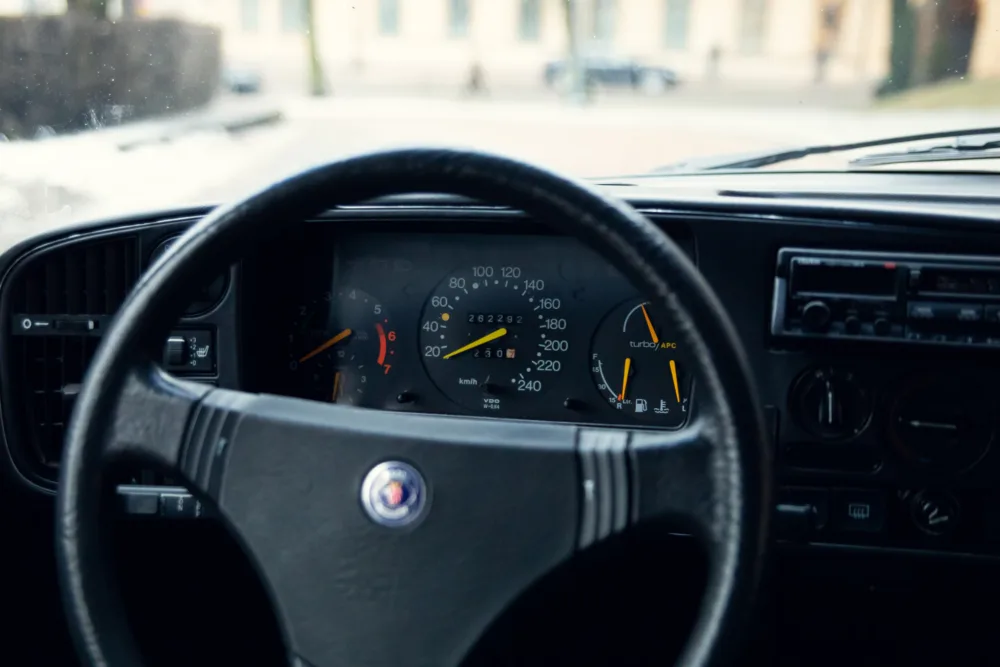 Car dashboard and steering wheel from driver's perspective.