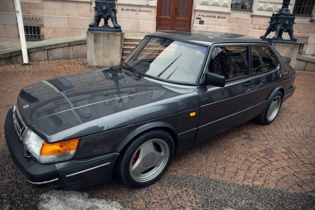 Vintage black sedan parked on cobblestone street.