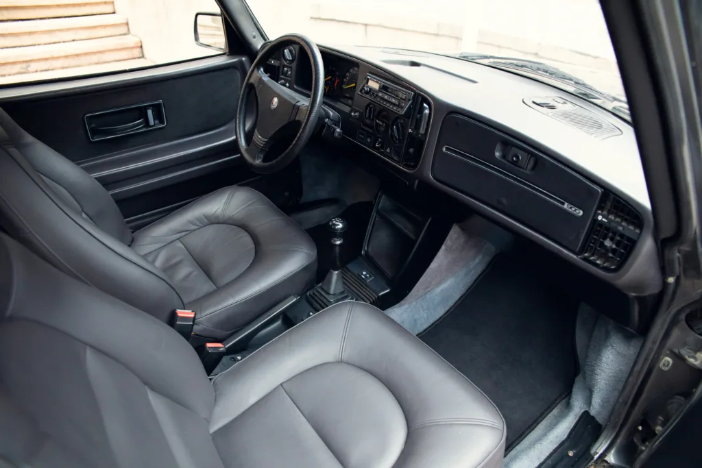 Vintage car interior with leather seats and manual transmission.