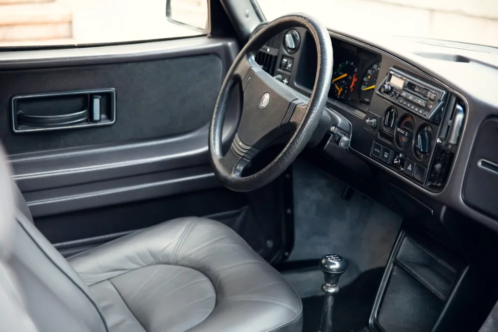 Classic car interior with leather seats and manual transmission.