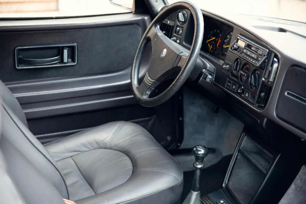 Vintage car interior with leather seat and manual gearshift.
