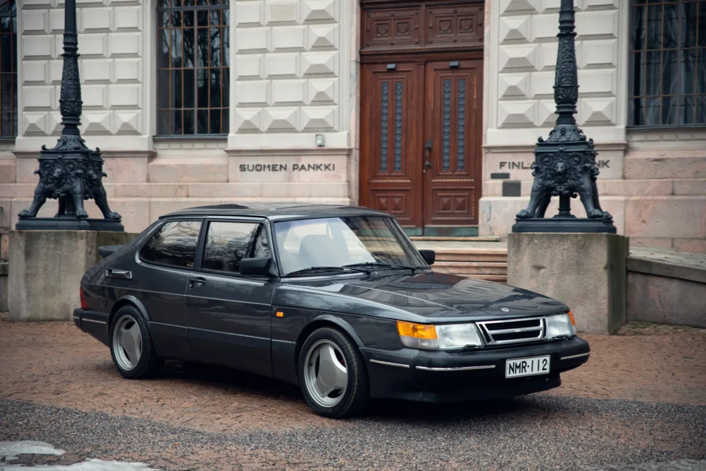 Vintage Saab car in front of building.