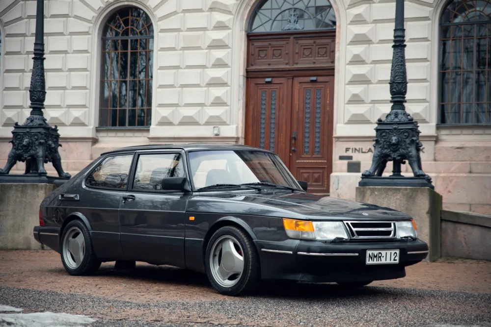 Vintage Saab car parked outside historic building.