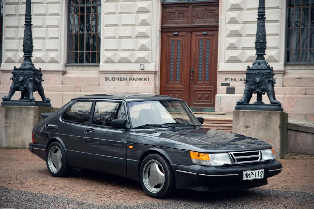 Vintage Saab car in front of building.