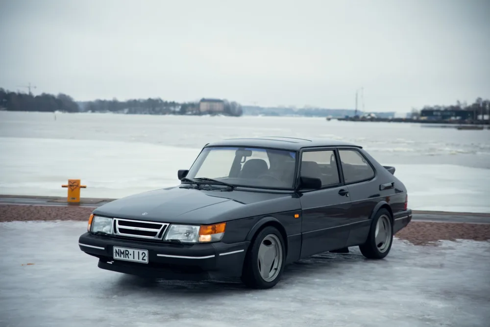 Vintage car parked on icy lakeside.