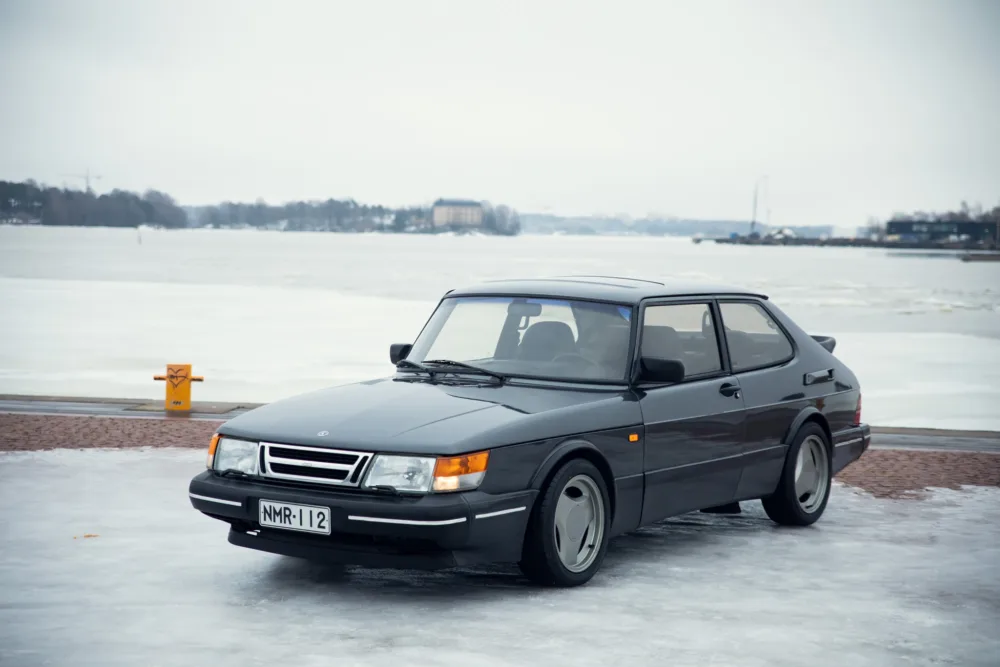 Vintage car parked on frozen lakeside.