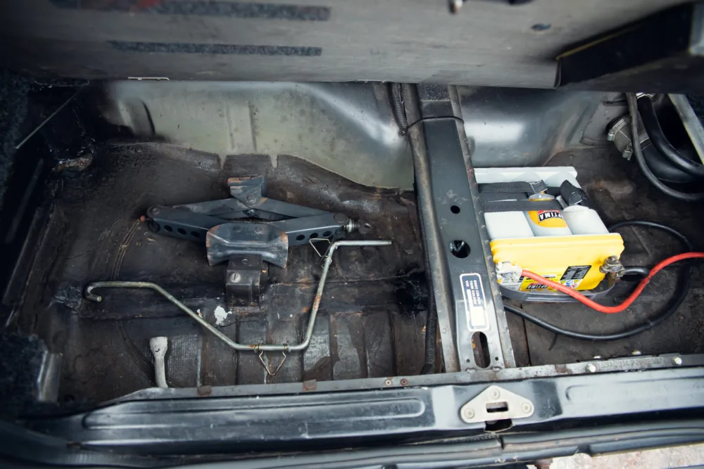 Empty car trunk with battery and jumper cables