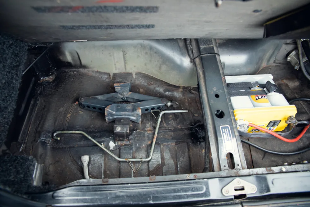 Car trunk with spare tire tools and battery.