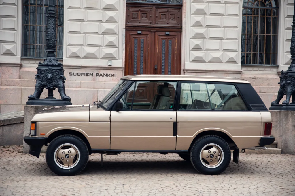 Vintage beige SUV parked near ornate building.