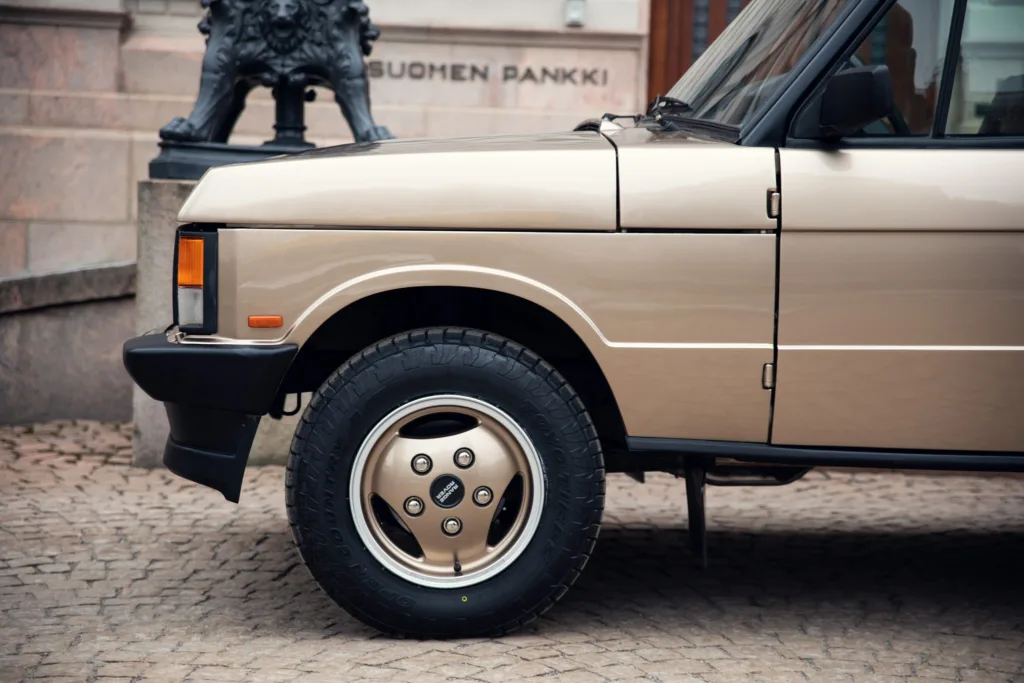 Beige vintage car parked near building.