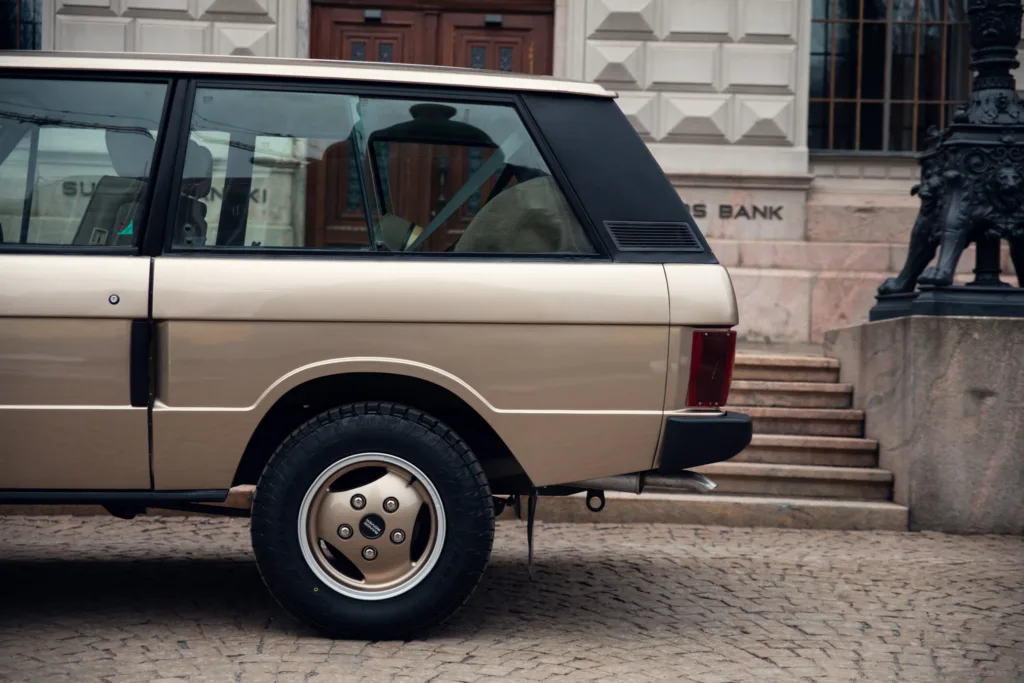 Vintage car parked near historic building steps.