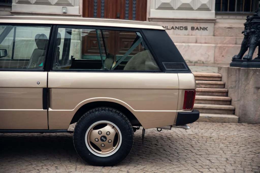 Vintage beige car parked by building steps.