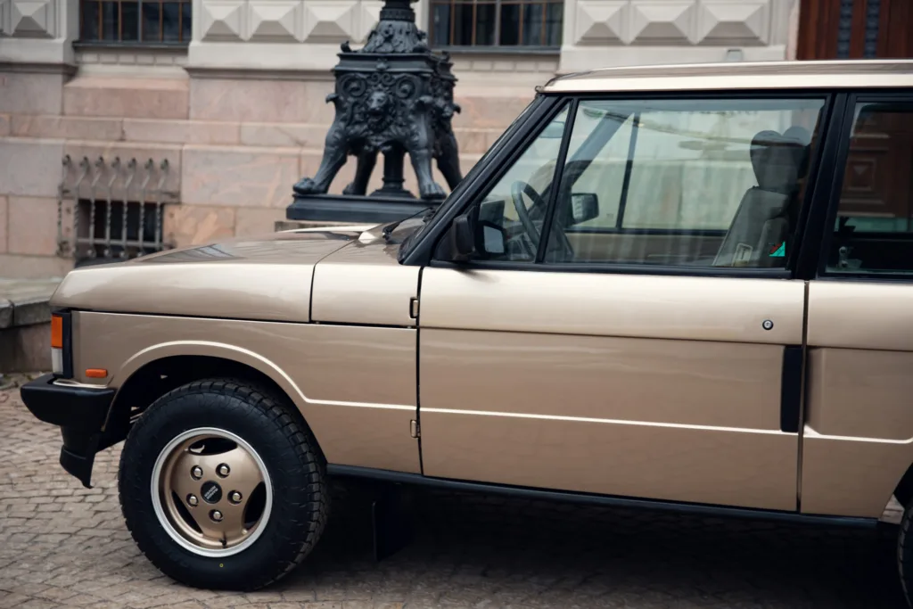Vintage SUV parked near historical building.