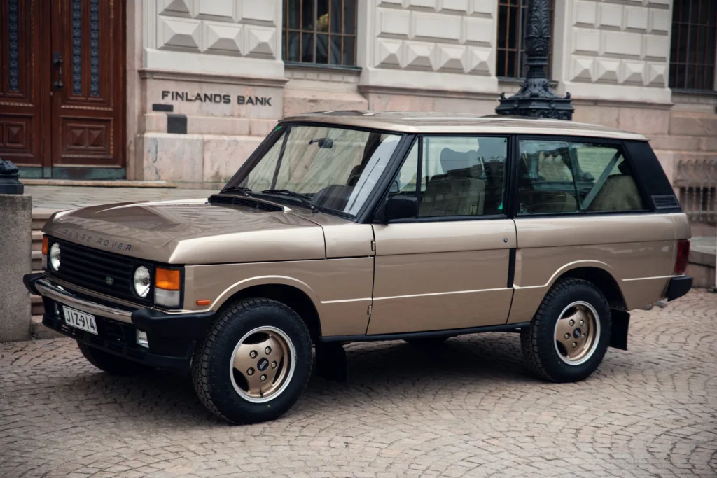 Vintage luxury SUV parked on cobblestone street.