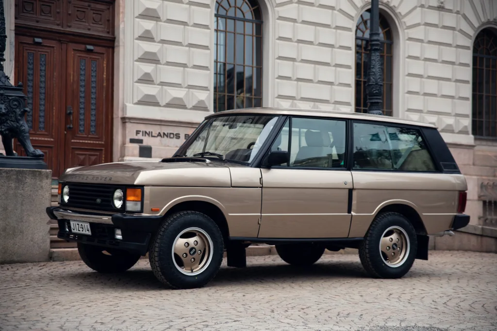 Vintage Range Rover parked by historic building.