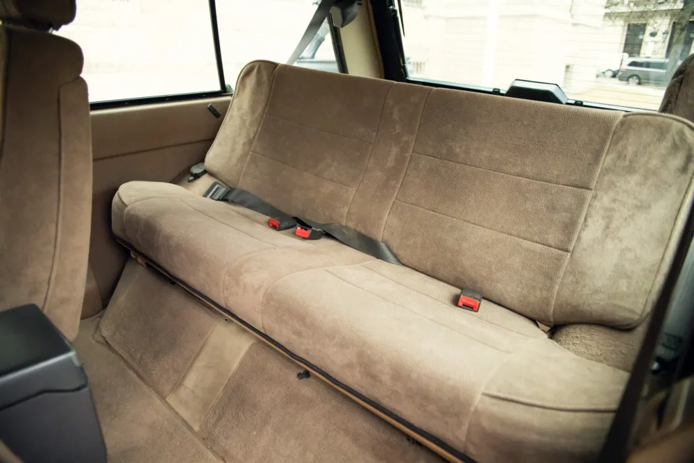 Beige car rear seat with seatbelts.