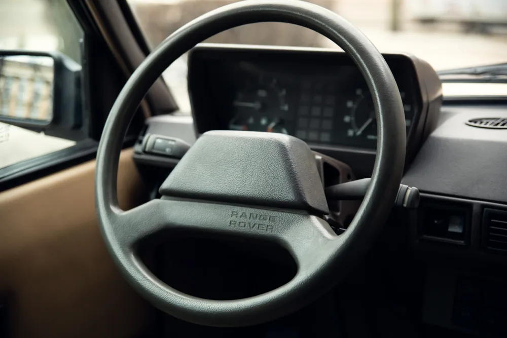Vintage vehicle interior, steering wheel, dashboard view.