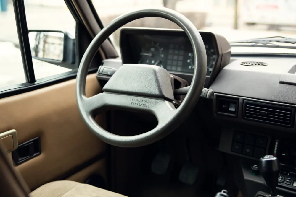 Interior of vintage Range Rover, steering wheel and dashboard.