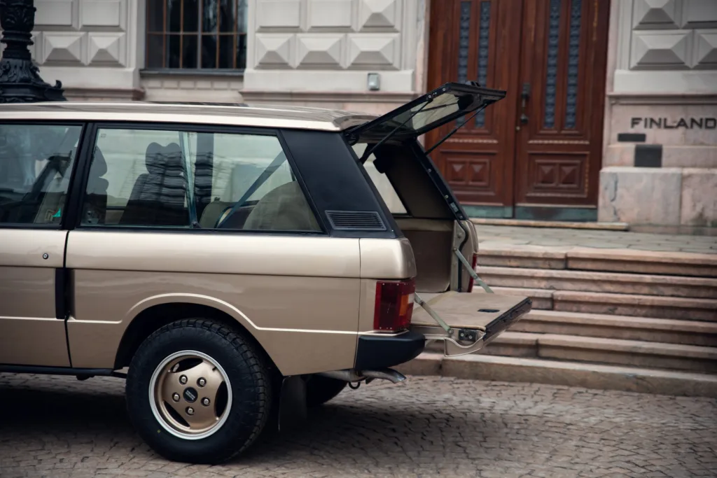 Vintage station wagon with open trunk at building entrance.