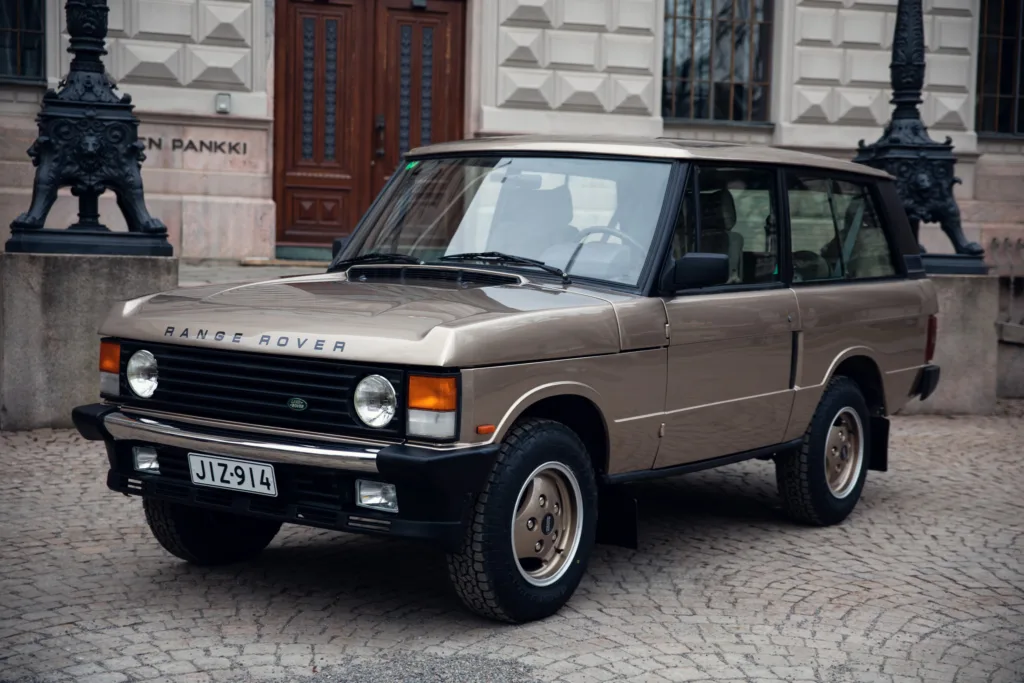 Vintage Range Rover parked on cobblestone street.