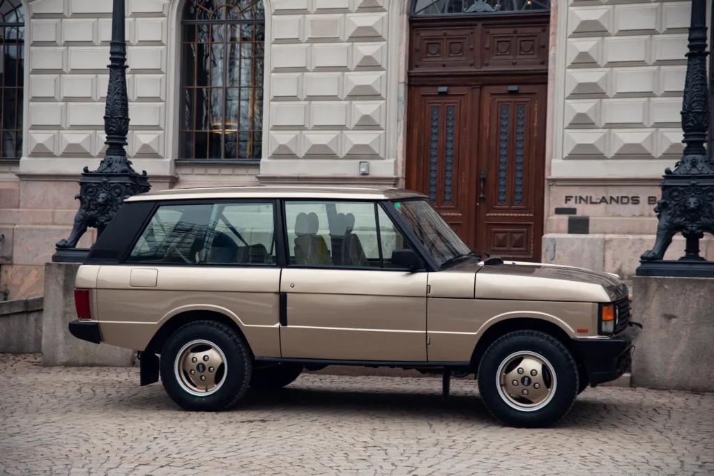 Vintage two-tone SUV parked on cobblestone street.