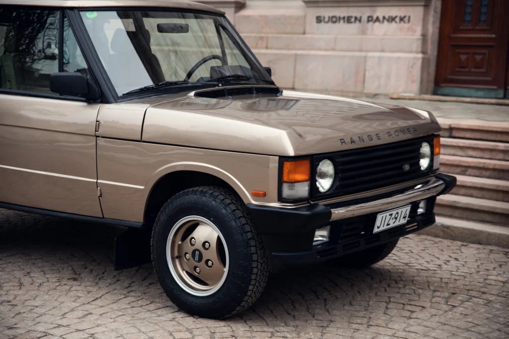 Vintage Range Rover parked on cobblestone street.