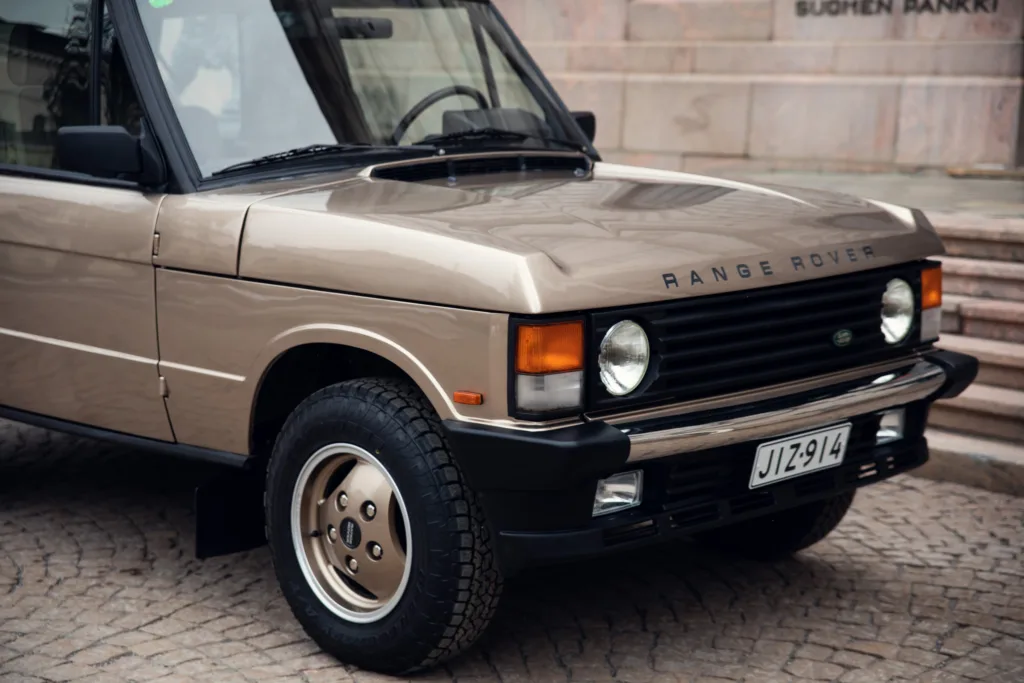 Vintage Range Rover parked on cobblestone street.