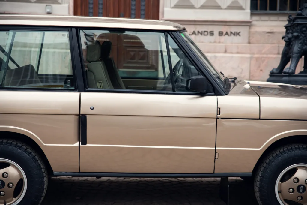 Vintage beige SUV parked on city street.