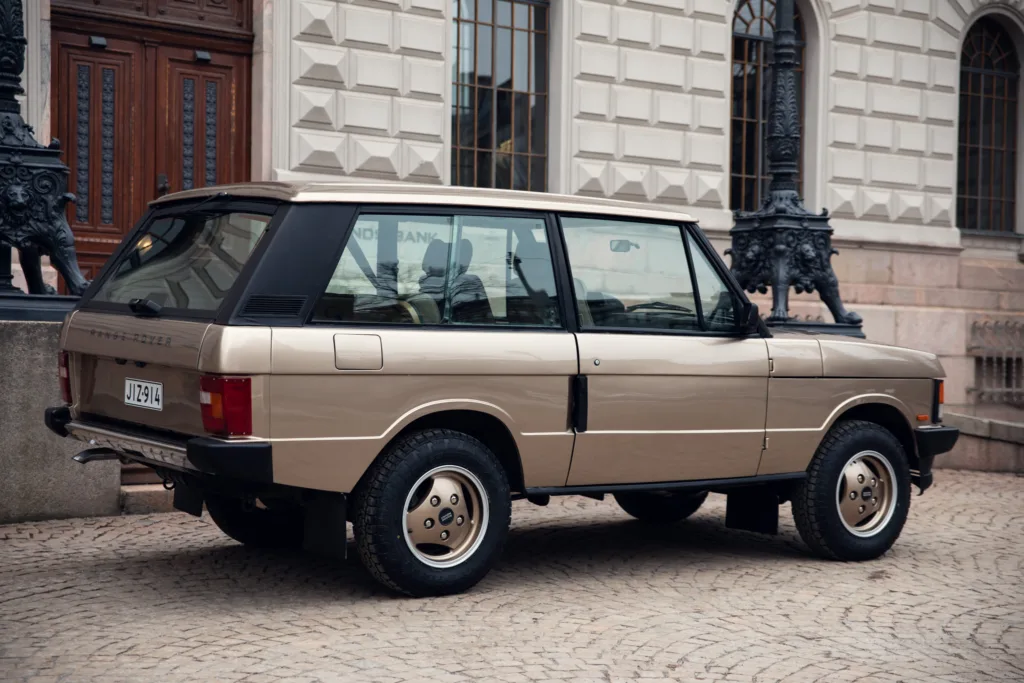 Vintage Range Rover parked by stone pavement.