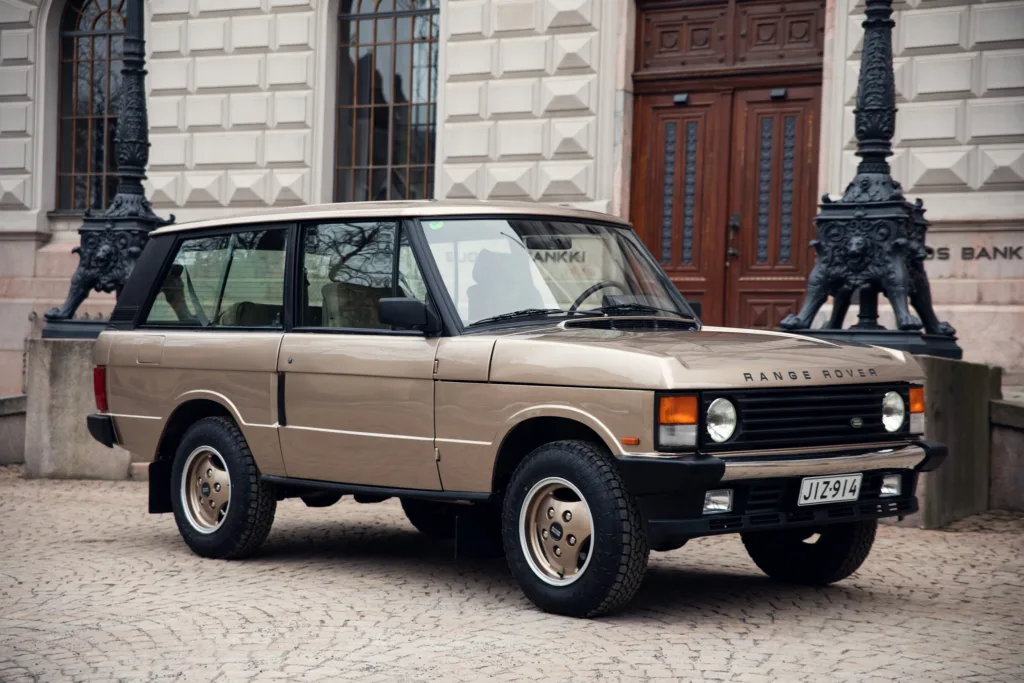 Vintage Range Rover parked on cobblestone street.