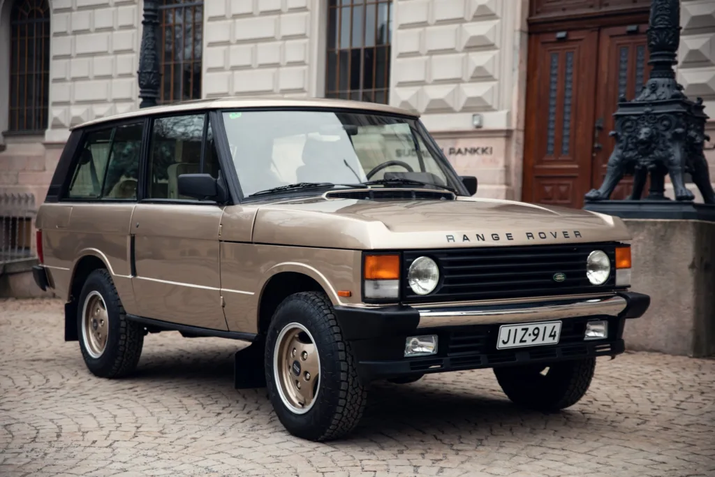 Vintage Range Rover parked on cobblestone street.