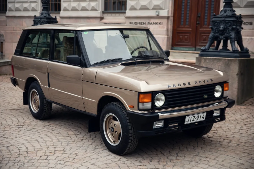Vintage Range Rover parked on cobblestone street.