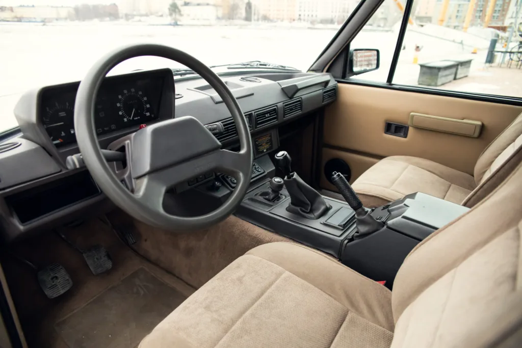 Vintage car interior with steering wheel and gear shift.