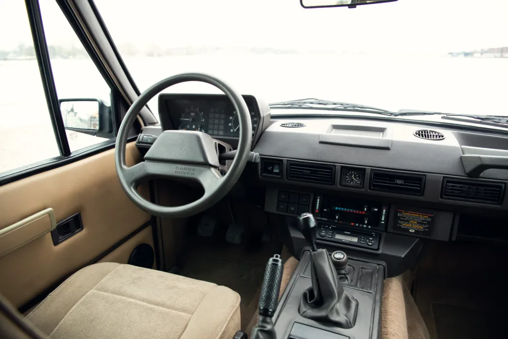 Vintage Range Rover interior with steering wheel and dashboard.