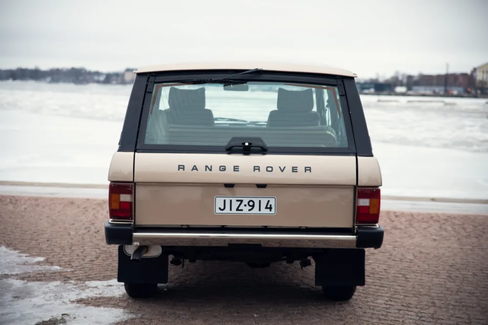 Classic Range Rover parked near icy water.