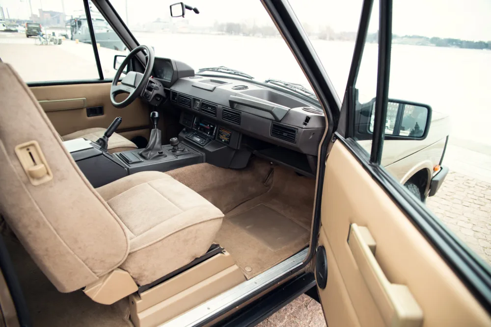 Interior view of vintage beige car with manual transmission.