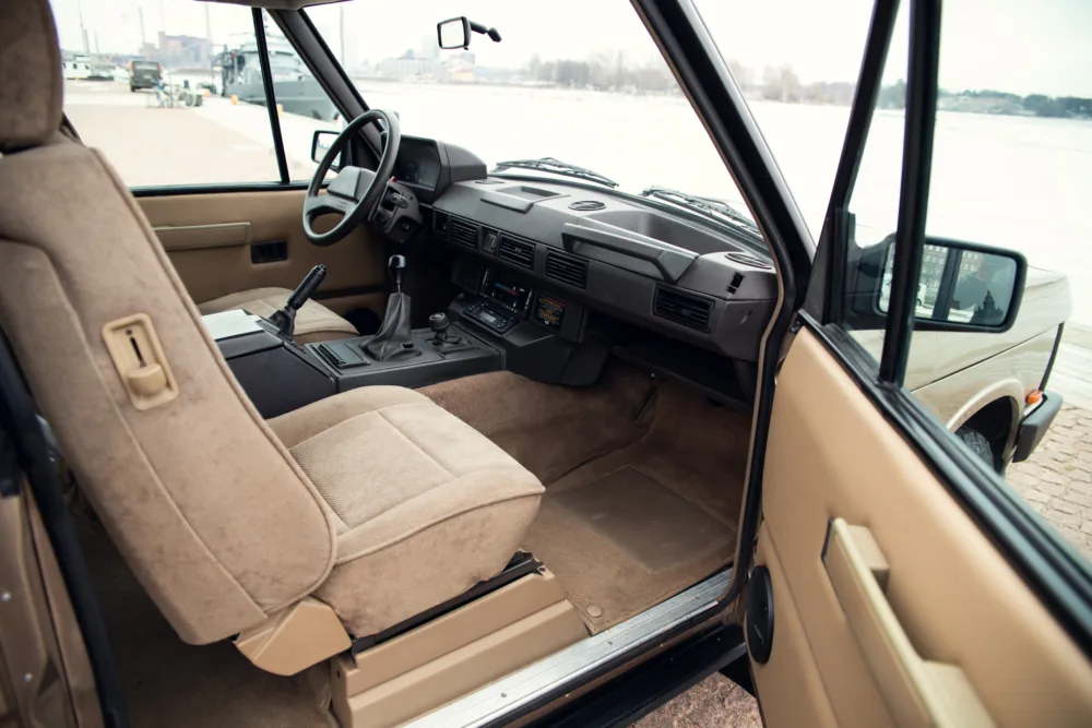 Vintage car interior, beige seats, manual transmission.