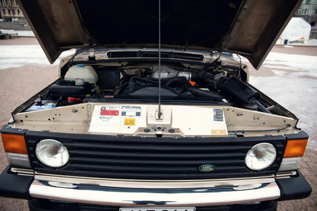 Open hood of vintage Land Rover showing engine.