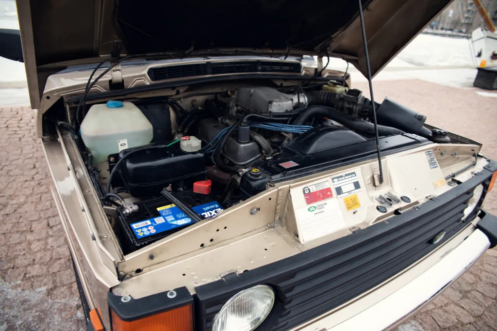 Car engine compartment open showing parts.