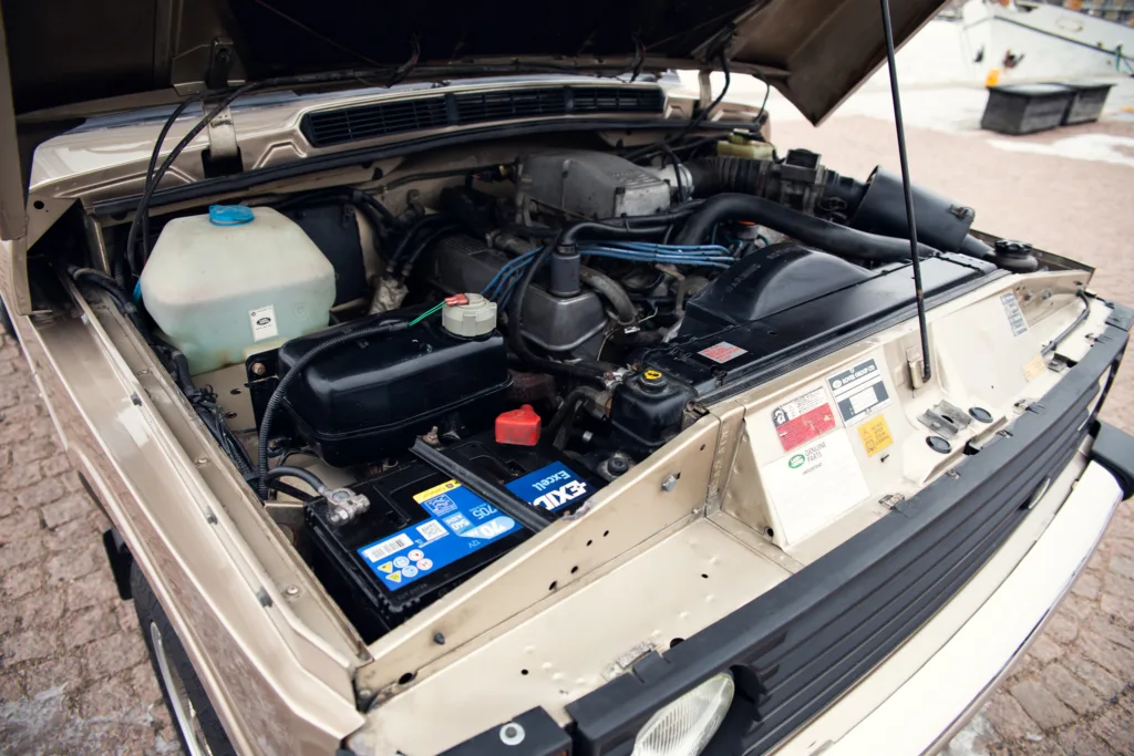 Open car hood showing engine and battery.