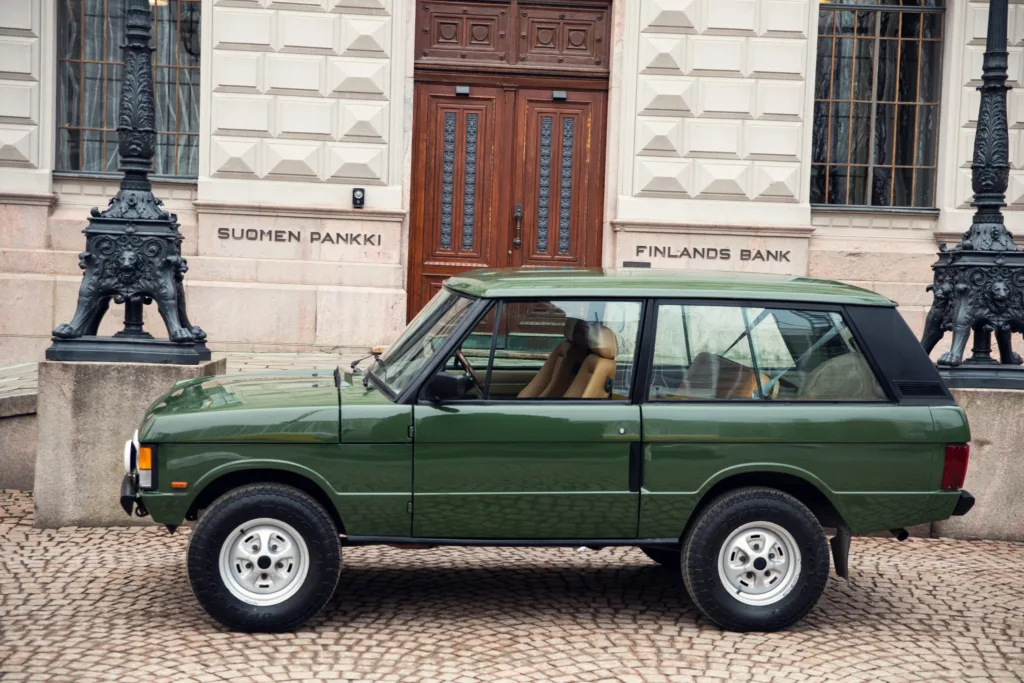 Vintage green SUV parked in front of historic bank building.