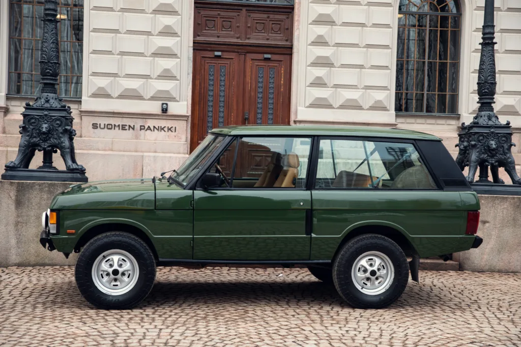 Vintage green SUV parked near historic building.