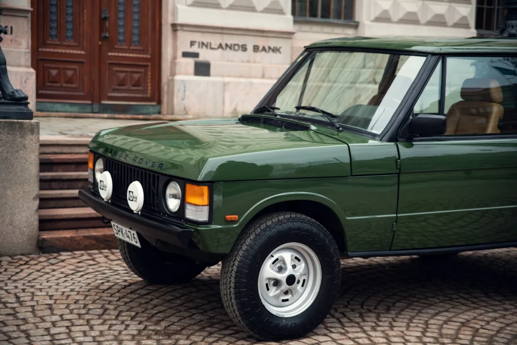 Vintage green Range Rover parked on cobblestone street.