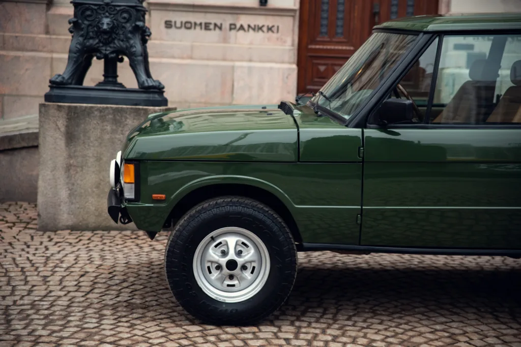 Green vintage car parked near historic building.