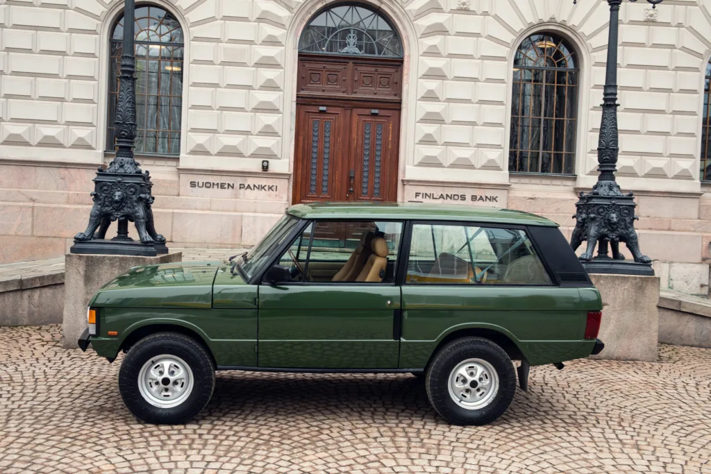 Green vintage car parked by historic building.