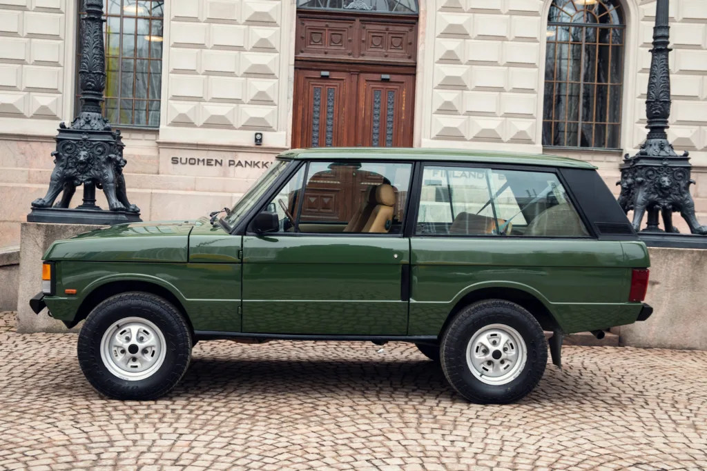 Vintage green SUV parked outside historic building.